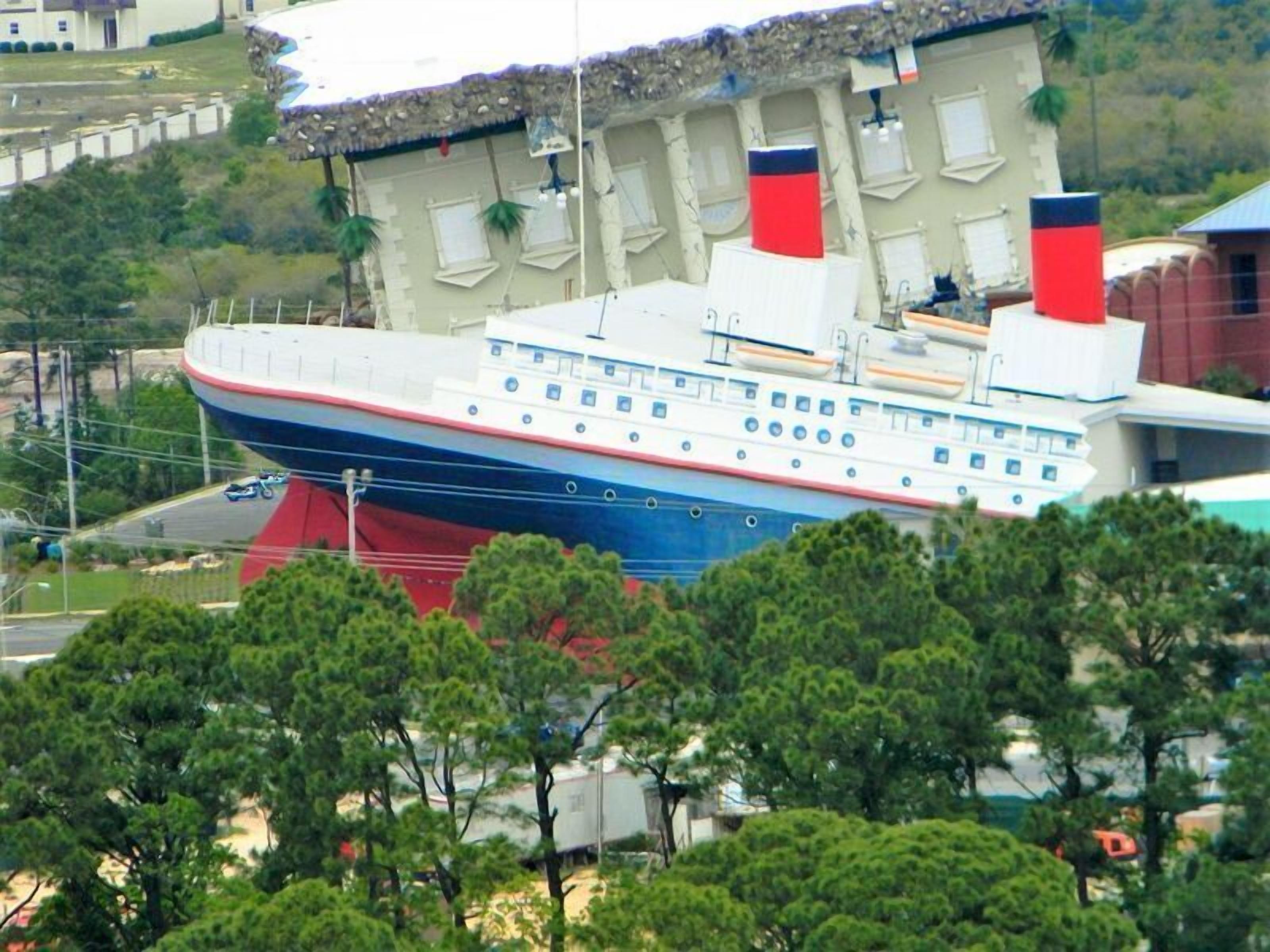 A large cruise ship docked at a port with multiple decks and lifeboats visible.