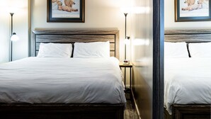 Habitación de hotel con una cama grande, dos mesitas de noche, un buró y dos cuadros en la pared.