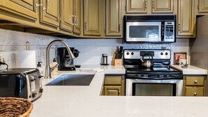 Una cocina con gabinetes de madera, un microondas de acero inoxidable, una estufa y un lavabo.