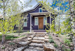 A house with a stone staircase leading to the front door, surrounded by trees and a well-maintained garden. - Plum Cottage: Gorgeous Historic Home (Breckenridge)