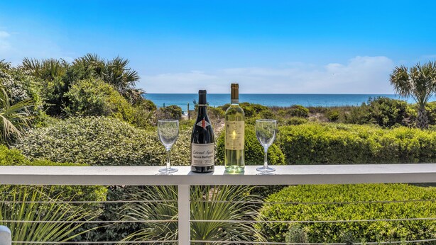 A balcony with a view of the ocean, a bottle of wine, and two glasses. - Beautiful ocean front townhome in the heart of WB! (Wrightsville Beach)