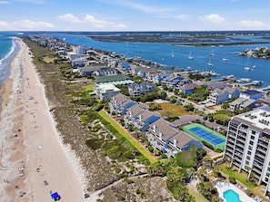 A coastal resort with a beach, marina, and several buildings with balconies.