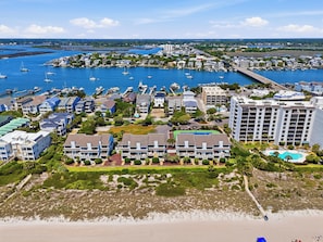 Un hôtel situé sur la côte, composé de plusieurs bâtiments, avec un port de plaisance et des bateaux, ainsi qu’une plage.