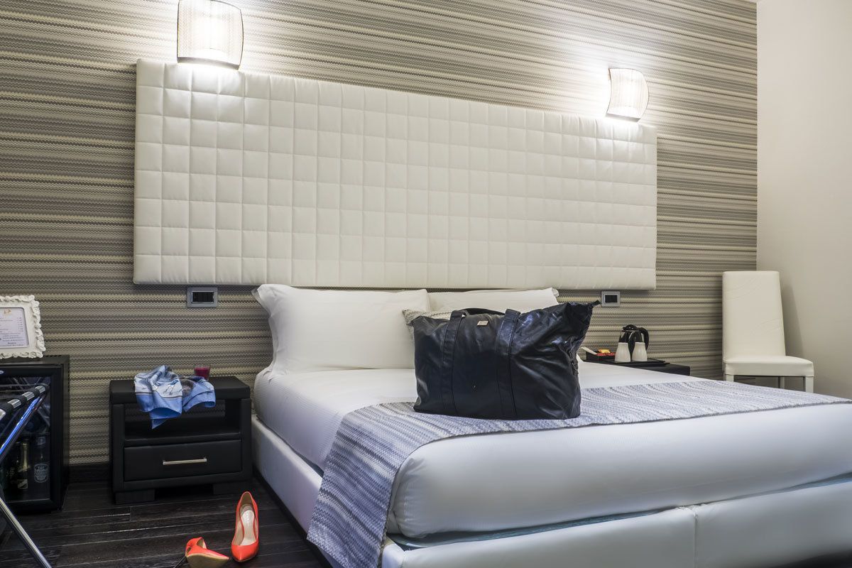 Habitación de hotel con una cama grande, una mesita de noche, una silla y una pequeña mesa con una lámpara.