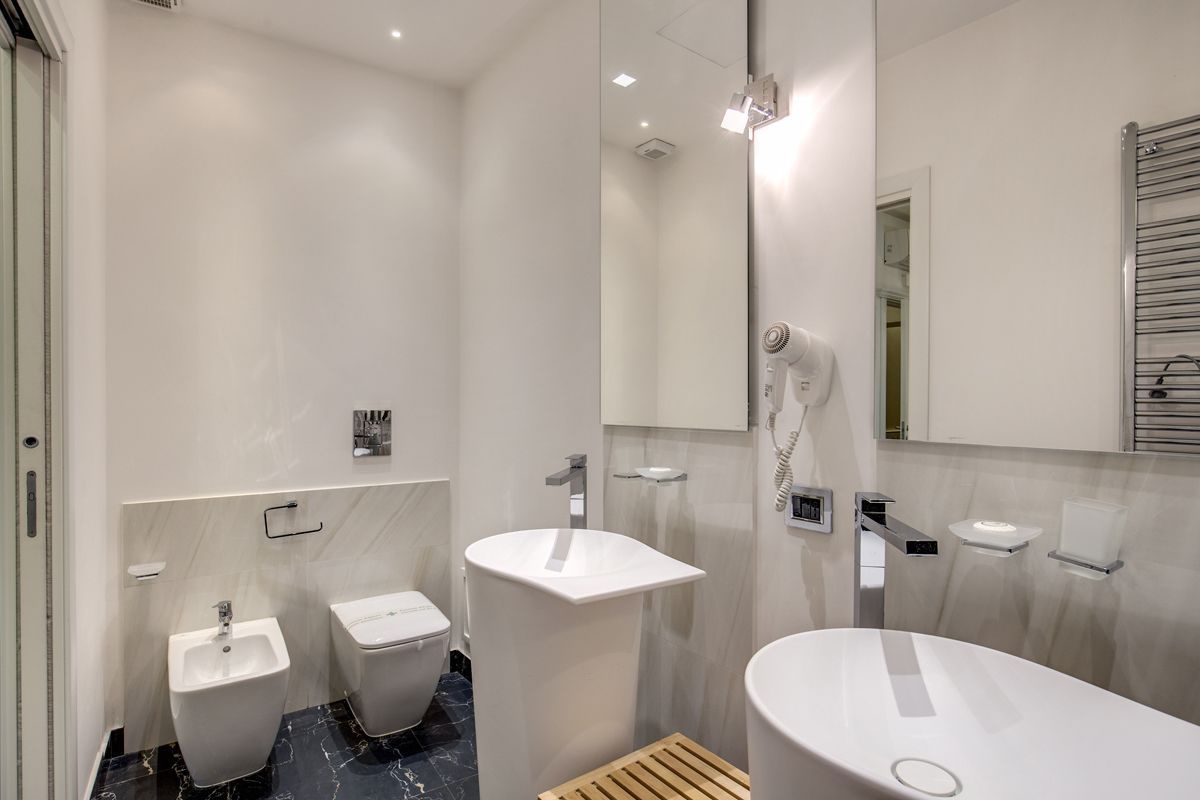 Uma casa de banho moderna com chuveiro, duas pias e um espelho grande.