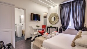 A modern hotel room with a bed, a desk, a chair, a TV, and a bathroom visible through an open door. - Navona Living Rome (Rome)