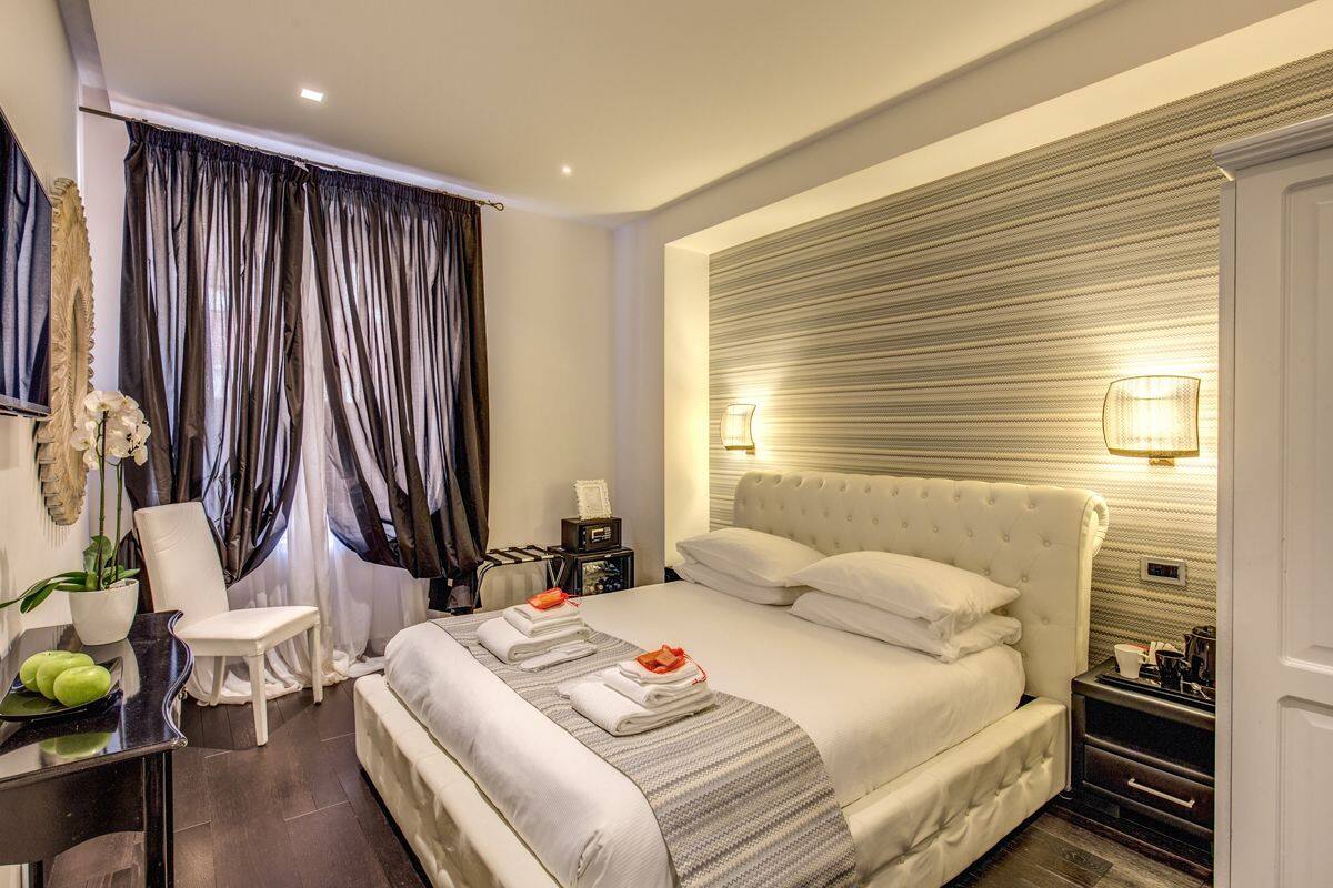 Une chambre d’hôtel moderne avec un grand lit, une table de chevet, une chaise, un bureau et une plante en pot.