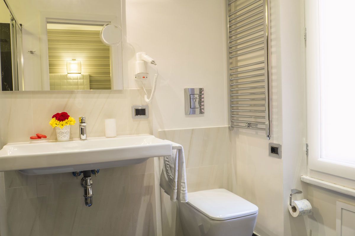 A bathroom with a white sink, a mirror, a hairdryer, a toilet, and a towel rack.