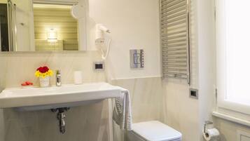 A bathroom with a white sink, a mirror, a hairdryer, a toilet, and a towel rack.