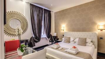 A hotel room with a large bed, a round mirror, a red chair, a glass table, and a potted plant.