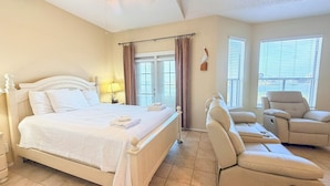 Une chambre d’hôtel avec un lit, une chaise, une lampe et une fenêtre avec des stores.