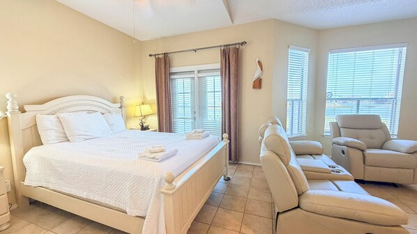 Une chambre d’hôtel avec un lit, une chaise, une lampe et une fenêtre avec des stores.