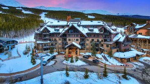 A large lodge with multiple balconies and a ski slope in the background.