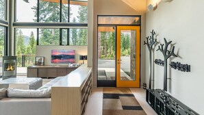 Una sala de estar moderna con chimenea, ventanas amplias y vistas al exterior.