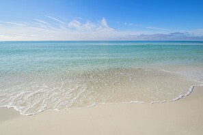 Enjoy a serene beach experience with calm waters gently lapping onto the shore.