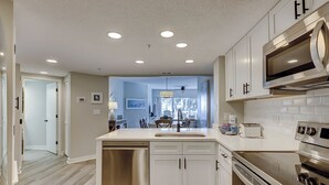 Una cocina moderna con armarios blancos, electrodomésticos de acero inoxidable y una isla central con fregadero.
