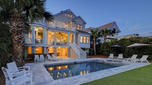 A large house with a swimming pool, multiple balconies, and outdoor seating.