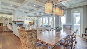 A spacious dining area with a large wooden table and wicker chairs, a built-in island with seating, and pendant lighting.