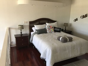 Une chambre à coucher bien aménagée, avec un grand lit, deux tables de chevet et une petite table d’appoint.