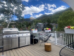 Une terrasse avec un barbecue, une chaise et une vue sur les montagnes.