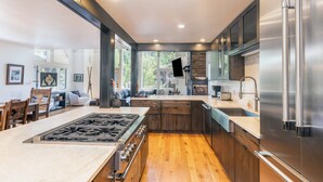 A modern kitchen with a central island, stainless steel appliances, and wooden flooring.