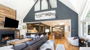 A spacious living room with a fireplace, a large TV, and a cozy seating area.