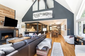Relax in this stylish living area with a high ceiling, fireplace, and comfortable seating options.
