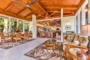Relax in this open-plan living area with a high ceiling, featuring a comfortable sofa, dining table for four, and a central kitchen island.