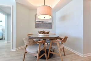 Uma área de refeições com mesa redonda, cadeiras de madeira e luminária pendente.