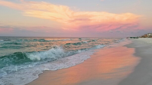 Ein Strand mit Wellen und einem Sonnenuntergang.