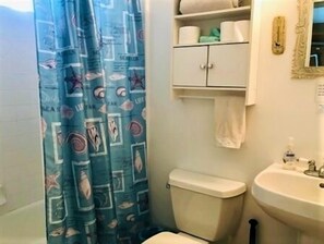 Un baño con inodoro, lavabo y un armario sobre él.