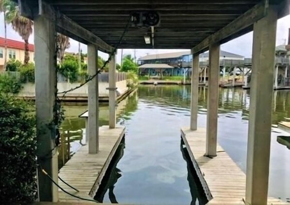 Un área de muelle cubierta con un pasillo de madera sobre el agua, sostenido por pilares de hormigón.