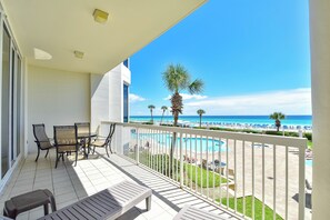 A balcony with a pool, chairs, and a view of the beach and ocean. - Tommy Bahama themed beachfront condo w/private balcony! (Destin)