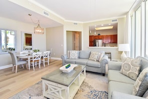 A spacious living room with a dining area, a kitchen, and a view of the ocean.