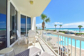 Un balcón con vista a la playa y una piscina.