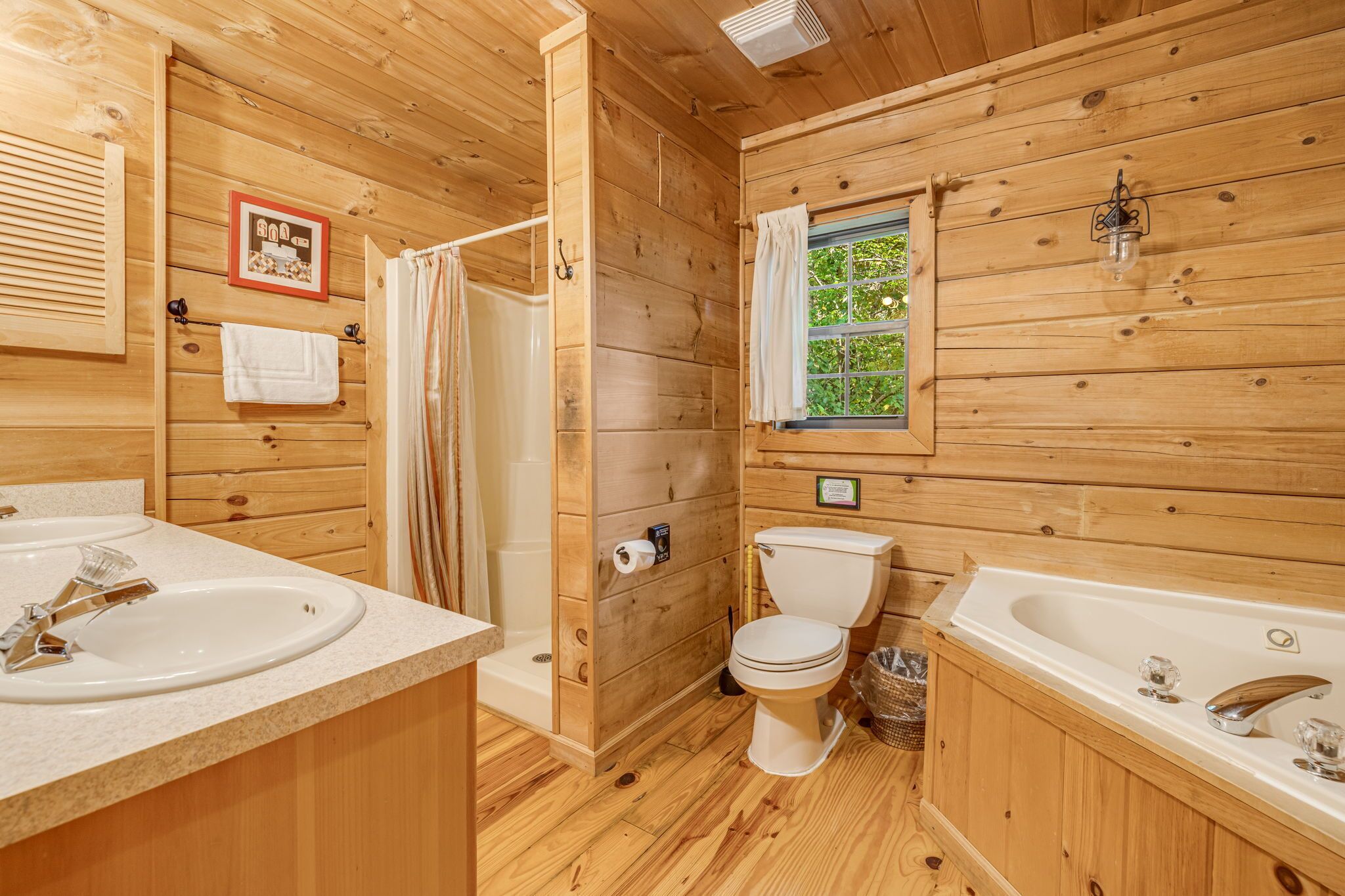 Une salle de bain rustique, avec deux lavabos, des toilettes et une baignoire.