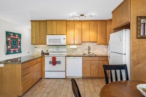 A kitchen with wooden cabinets, a microwave, a stove, a dishwasher, and a refrigerator.