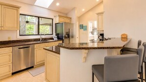 Een moderne keuken met een centraal eiland, roestvrijstalen apparatuur en een groot raam.