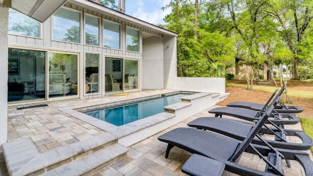 Een modern huis met een zwembad, terras en tuin.