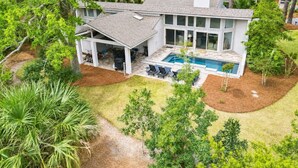 Een modern huis met een overdekt terras, een zwembad en een verzorgd gazon.