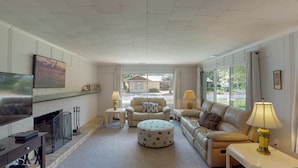 A living room with a fireplace, a sofa, a coffee table, and a TV. - Bradfield 4 bedrooms, 2.5 bathrooms (Jekyll Island)