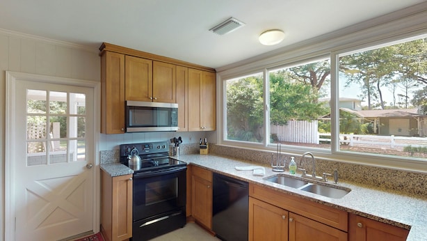 A kitchen with wooden cabinets, a stainless steel sink, a microwave, and a stove. - Bradfield 4 bedrooms, 2.5 bathrooms (Jekyll Island)