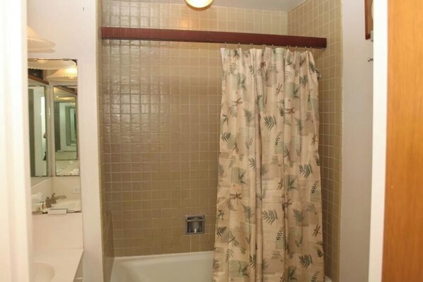 Ein Badezimmer mit einer Badewanne, einer Duschvorhang und einer gefliesten Wand.