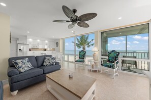 A modern living room with a sofa, coffee table, and chairs, a ceiling fan, and a view of the ocean. - Island Beach Club #360D is a 2/2 vacation rental on Sanibel Island! (Sanibel)