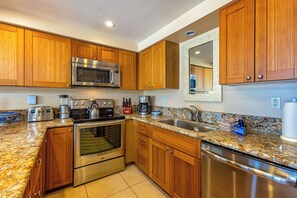 Eine Küche mit Holzausstattung, Edelstahlgeräten, Granit Arbeitsplatten und einem eingebauten Backofen.