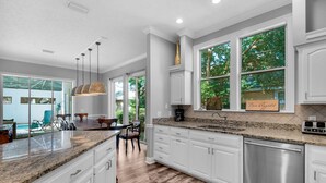 A modern kitchen with white cabinetry, granite countertops, and a stainless steel dishwasher. - Pet Friendly Home-Private Pool-2 Golf Carts-4 Bikes (Destin)