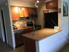 A modern kitchen with wooden cabinets, stainless steel appliances, and a granite countertop.