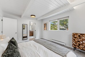 Un dormitorio moderno con una cama grande, un vestidor, una ventana con vistas y una lámpara en el techo.
