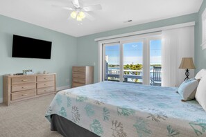 A bedroom with a bed, a dresser, a television, and a balcony with a view. - Conley A Sound Front Townhome with Boat Slip! (Wrightsville Beach)