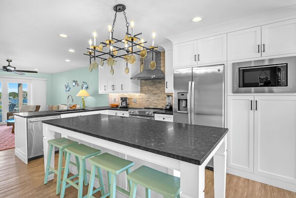 A modern kitchen with a central island, stainless steel appliances, and a chandelier. - Conley A Sound Front Townhome with Boat Slip! (Wrightsville Beach)